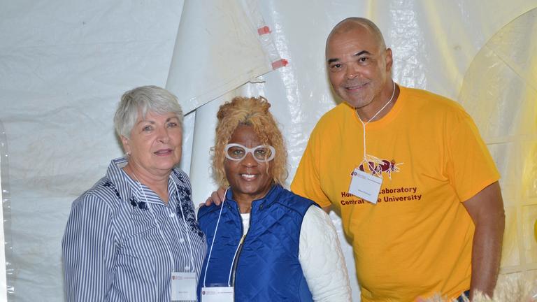 three people stand together while smiling at the camera