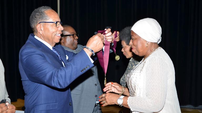 central state university interim president dr. alex johnson prepares to place a medallion over the head of a member of the class of 1974