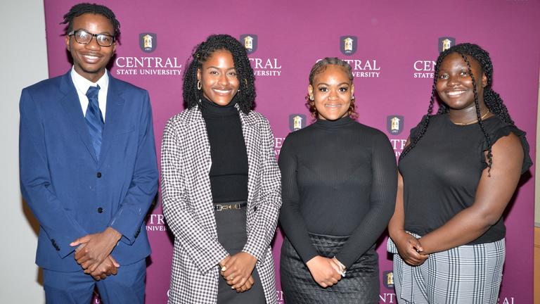 Students stand in front of a central state university backdrop