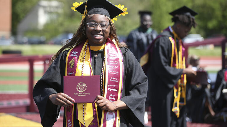 a graduate holds her diploma after walking the stage