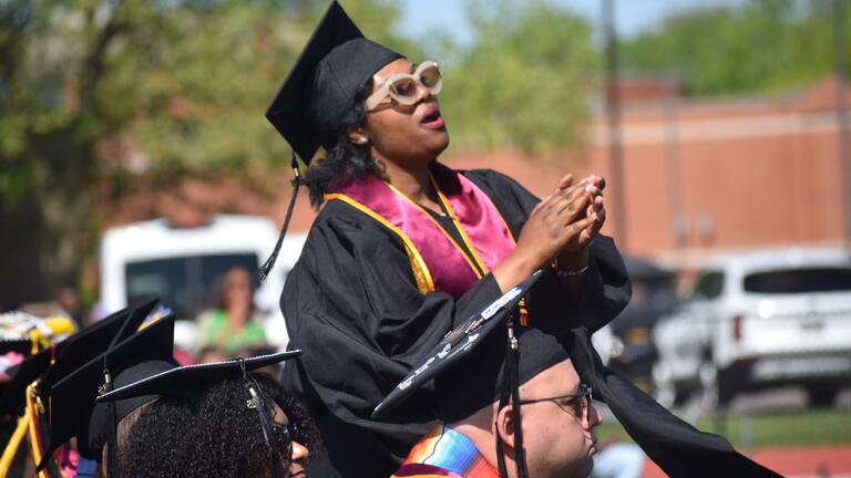 a graduates sings out among the seated crowd