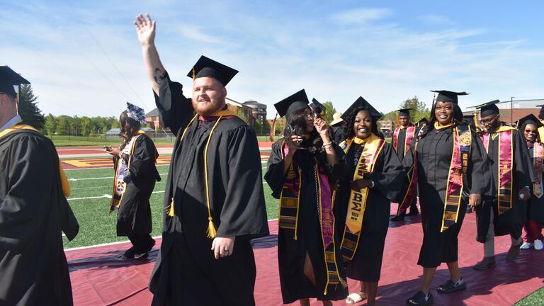 a graduate waves from the processional