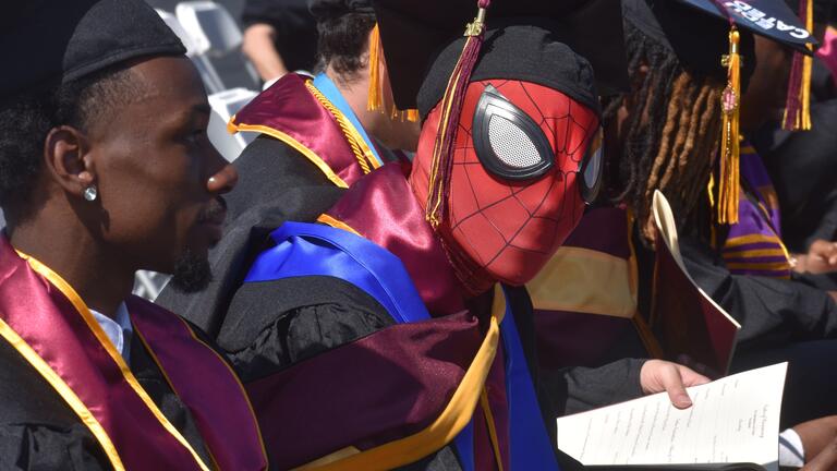 a graduate wears a spiderman mask