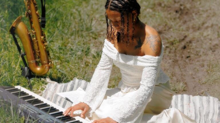 kamille austin playing keyboard with saxophone beside her