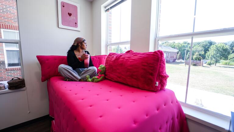 CSU Dorm Life 2026 - Female Student in her dorm room looking ot the window