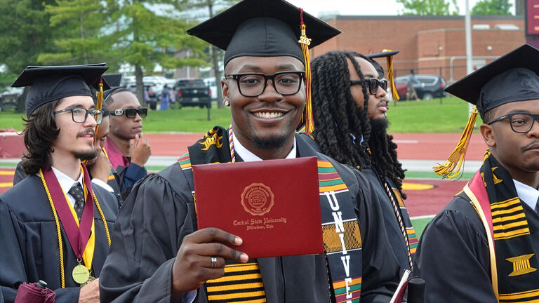 a graduate proudly holds his diploma