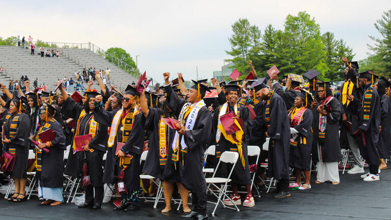 graduates stand in front of their seats