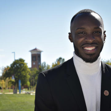 An African American student wears a Central State University Presidential Seal lapel pin while standing on the historic campus in Wilberforce