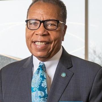 A man wearing a black suite jacket and blue tie