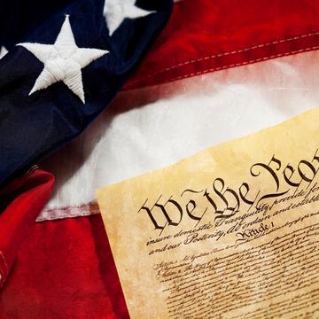 A closeup of the U.S. Constitution and flag