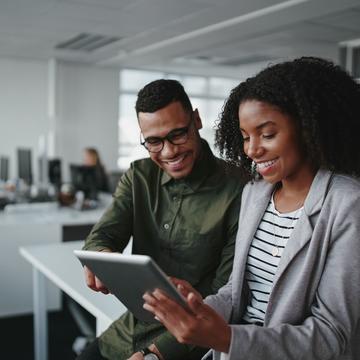 Smiling young african american professional businessman and businesswoman together working online with a digital tablet in office