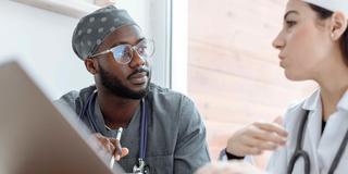 A Black healthcare worker collaborates with a colleague.