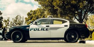 a police vehicle sits in a parking lot while an officer protects and serves