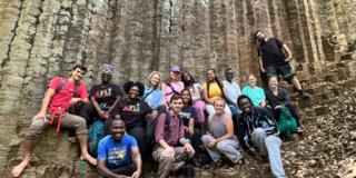 A group of young adults sits in front of sediment in Machame Kaskazini
