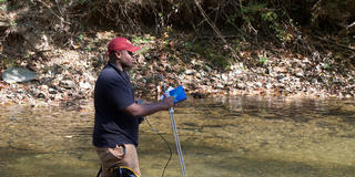 STEM student testing river water with diagnostic equipment
