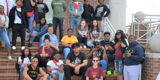 A large group of high school students in the TRIO Upward Bound program sit on a stairwell on the Central State University campus