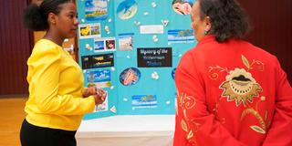 Central State University student shares a posterboard with information about Bahamas with a Wilberforce community member