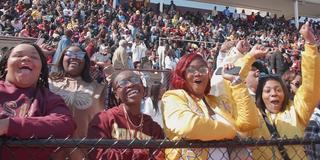 a group of students wearing maroon and gold, cheering on the Central State University Marauders football team