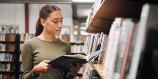 a young person browses the stacks at a library