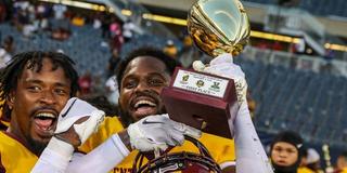 Two Marauder football players celebrate with a trophy from the Chicago Football Classic
