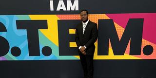 Central State University student Phanuel Cofie of Ghana stands in front of a colorful sign that says "I am S.T.E.M."