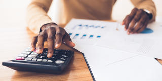 hands of an African American accountant working with a calculator and accounting materials
