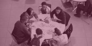 six students sit work together around a table in a bird's eye view with a maroon overlay