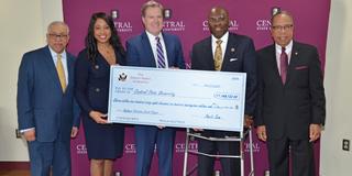 five people holding a large ceremonial check