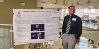 daquan neal stands beside his research poster on presidential rhetoric and its impact on voters