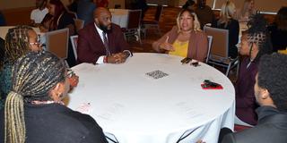 six people sit at a round table in a lively discussion at central state university