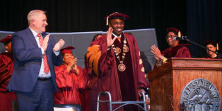 central state university president dr. morakinyo a.o. kuti waves from the stage while ohio department of higher education chancellor mike duffy looks on
