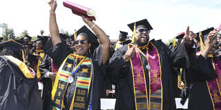class of 2025 graduates celebrate with their hands in the air during commencement