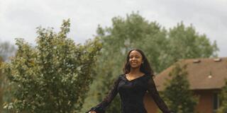 a young black woman with long brown hair wearing a black dress