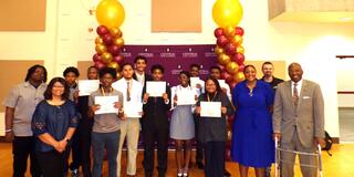 a large group of young adults standing with certifications for completion of the first honda american engeering academy at central state university