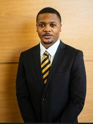 aden fisher wearing a black suit and gold and maroon striped tie
