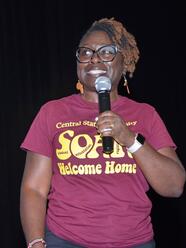 doctor tammi love holding a microphone wearing a shirt at soar student orientation advising and registration. the shirt also says welcome home.