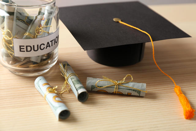 Jar of money beside a graduation cap