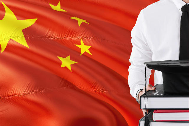 Student with Graduation hat on a stack of books in front of China's Flag