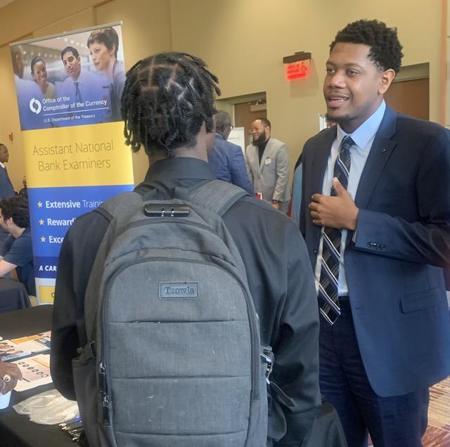Devin Watkins, a 2018 graduate of Central State University and Associate National Bank Examiner for the U.S. Department of Treasury, Office of the Comptroller of Currency, speaks with a student at the annual career fair.