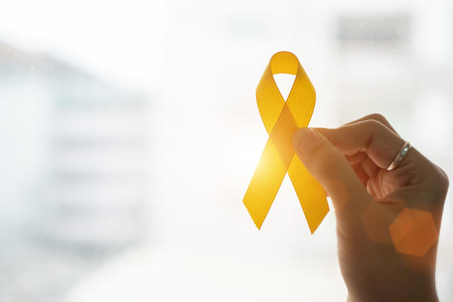 a hand holds a yellow ribbon for suicide prevention awareness counseling at central state