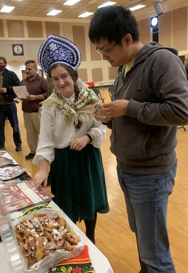 a person in Russian attire points to a display about her home country