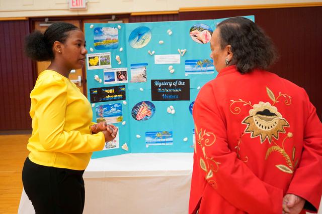 Central State University student shares a posterboard with information about Bahamas with a Wilberforce community member