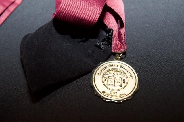 a gold medallion with the Central State University seal on a maroon landlord