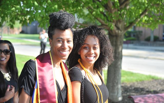 two central state university graduating seniors with cords and honors designations at commencement