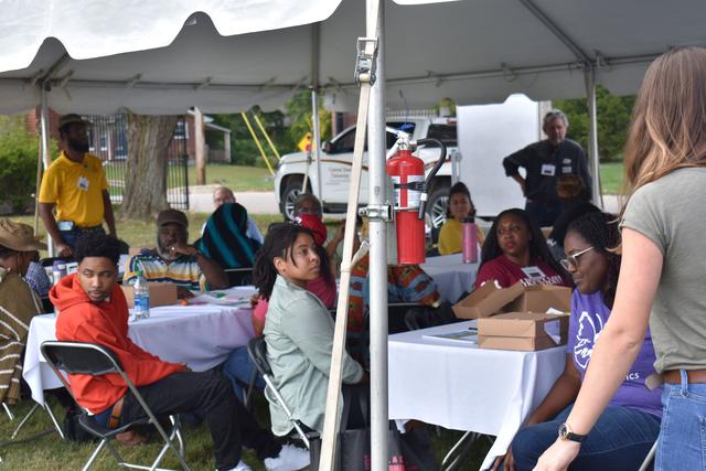 a large group of people sits under a tent at the 2023 land-grant open house at central state university