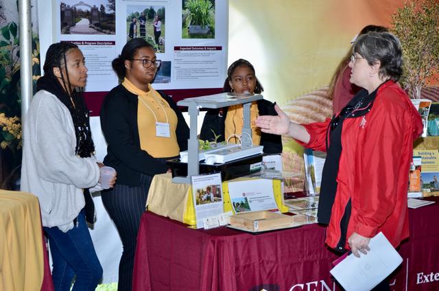 four people talk at a display table