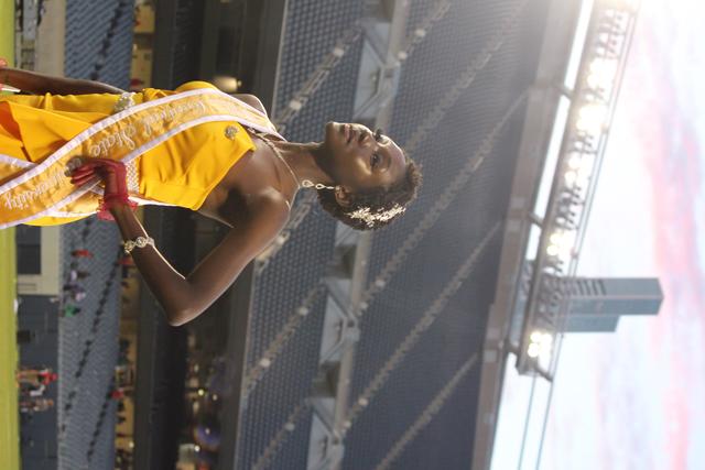 a black woman with short hair stands in a gold dress with a sash at william patrick mcpherson memorial stadium at central state university