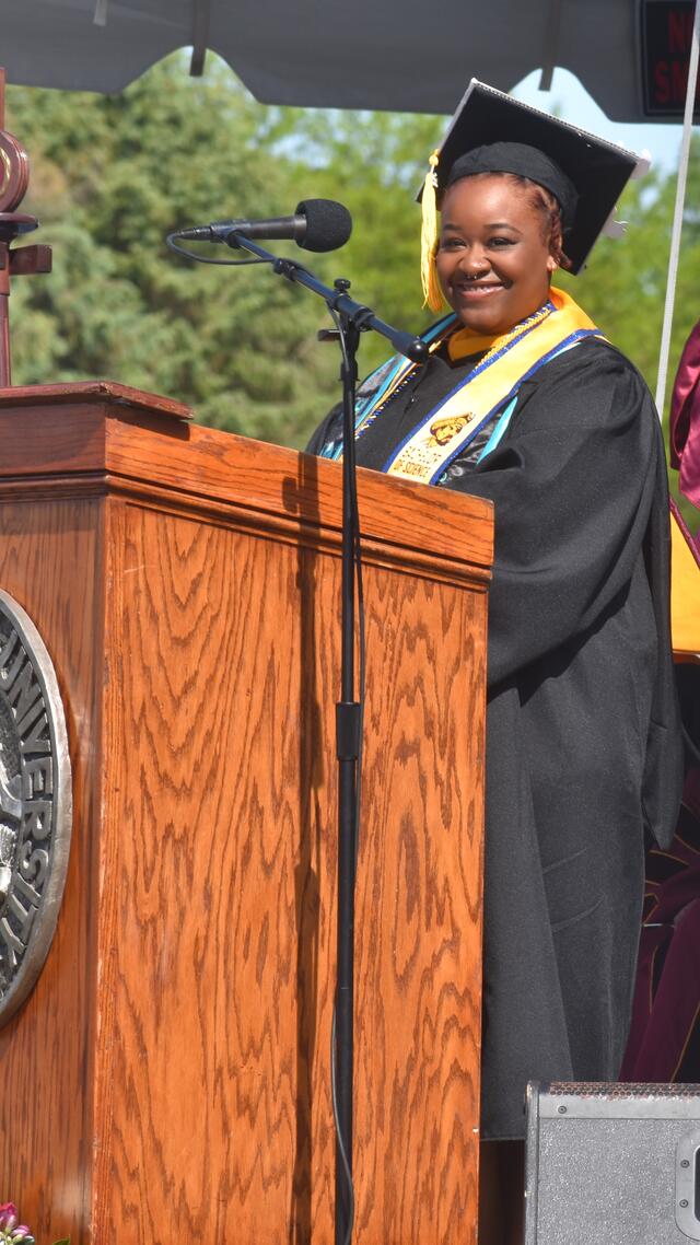 mer'kyah warren in cap and gown at podium during commencement