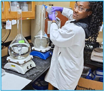 royalty hightower in a lab wearing a white lab coat and protective glasses