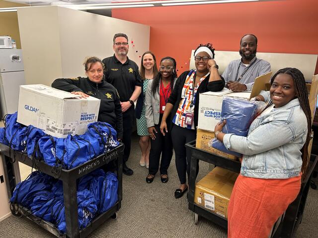 a group of people standing in an office with bags of hygiene items